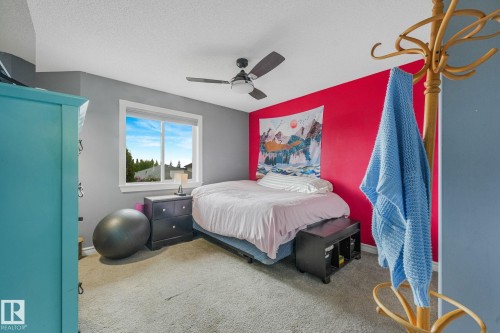 Bedroom featuring a window with exterior views, carpeted flooring, and a ceiling fan - 98 Bridgeport Wynd, Leduc, AB 