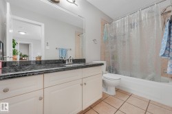 Bathroom featuring a white vanity with paneling and brushed nickel hardware, a dark-toned countertop, and an integrated sink with a chrome faucet - 