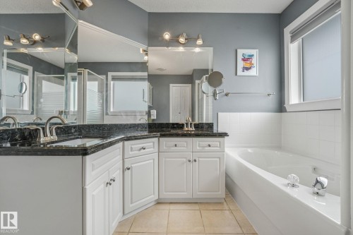 Double vanity with undermount sinks, dark stone countertops, and brushed nickel faucets - 98 Bridgeport Wynd, Leduc, AB 