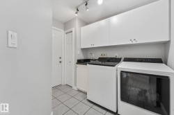 Laundry area featuring white cabinetry, dark countertop, and tile flooring - 