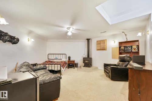 Spacious room featuring a wood-burning stove on a raised hearth, a ceiling fan, and recessed ceiling lighting - 98 Bridgeport Wynd, Leduc, AB 