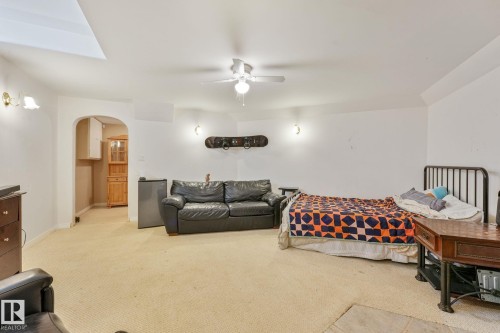 Spacious carpeted room featuring a ceiling fan with light, arched doorway, and built-in wall sconces - 98 Bridgeport Wynd, Leduc, AB 