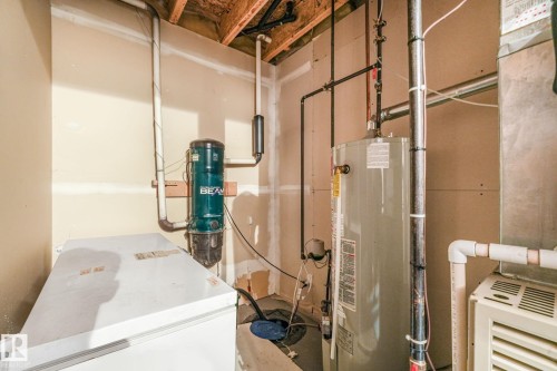 Utility area featuring a water heater, central vacuum system, and exposed ceiling joists - 98 Bridgeport Wynd, Leduc, AB 