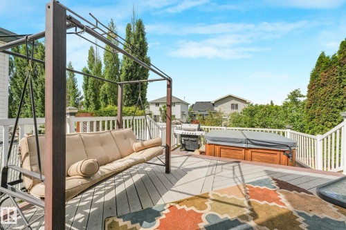 Spacious outdoor deck featuring wood-finish flooring, white railing, and a built-in spa - 98 Bridgeport Wynd, Leduc, AB 