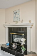 Fireplace with a black tile surround and hearth, featuring a white mantle with fluted pilasters - 