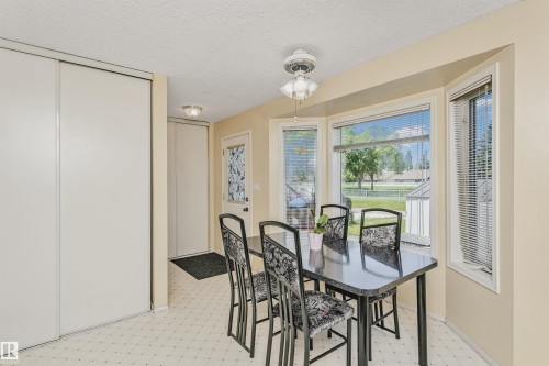 Dining area with bay window featuring horizontal blinds, recessed ceiling, patterned vinyl flooring, and a ceiling fan with light fixture - 1612 80A Street, Edmonton, AB 