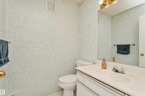 Bathroom featuring a single vanity with an integrated sink, polished chrome faucet, and a large wall-mounted mirror - 1612 80A Street, Edmonton, AB 