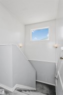 Staircase featuring a window, wall-mounted sconces, and carpeted steps - 