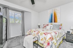 Carpeted bedroom with a window featuring horizontal blinds and drapery - 