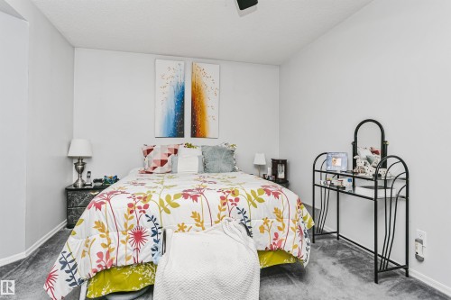 Bedroom featuring light gray wall paint, gray carpeting, a textured ceiling, and white trim - 1612 80A Street, Edmonton, AB 