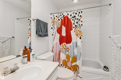 Bathroom featuring a white vanity with an integrated sink, a two-handle chrome faucet, and a toilet - 1612 80A Street, Edmonton, AB 