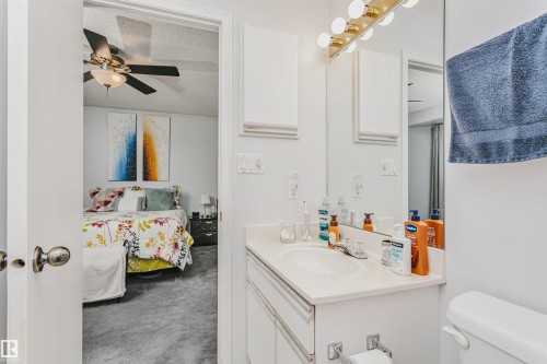 Bathroom vanity with integrated sink, white cabinetry, and a framed mirror - 1612 80A Street, Edmonton, AB 