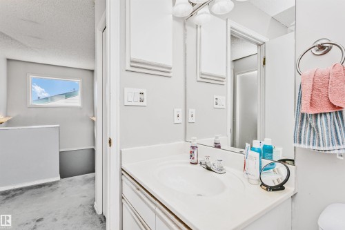 Bathroom vanity with an integrated sink, polished chrome faucet, and a large wall-mounted mirror - 1612 80A Street, Edmonton, AB 
