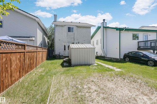 Expansive backyard featuring a wood fence with lattice top, a detached storage shed, and a stone paver pathway - 1612 80A Street, Edmonton, AB 