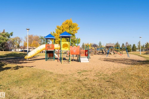 Community playground featuring multiple play structures, sand base, and surrounding green space with mature trees - 1612 80A Street, Edmonton, AB 