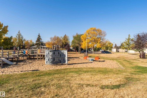 Outdoor recreation area featuring a sand-based playground with a slide, climbing structure, and teeter-totter - 1612 80A Street, Edmonton, AB 