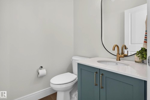Bathroom featuring a contemporary vanity with a teal cabinet, white countertop, and gold-finish faucet - 30 Rosewood Way, St. Albert, AB 