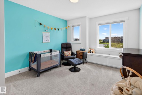 Light-filled room featuring two windows, a built-in window seat with storage, a vibrant accent wall, and neutral carpeting - 30 Rosewood Way, St. Albert, AB 