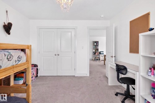 Plush grey carpeting complements bright white walls and trim, featuring a double-door closet with polished chrome hardware and a decorative overhead light fixture - 30 Rosewood Way, St. Albert, AB 