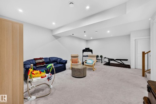Open-concept recreation area featuring light grey carpeting, recessed lighting, and white walls - 30 Rosewood Way, St. Albert, AB 