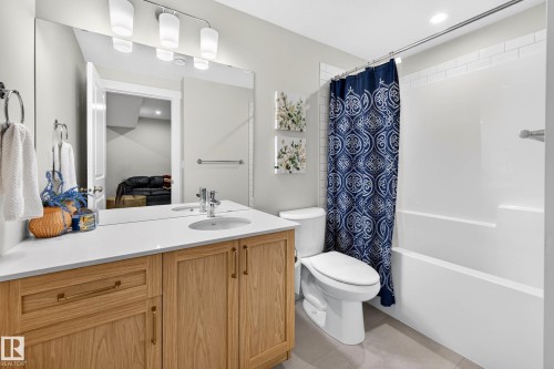 Bathroom featuring a wood-finish vanity with a white countertop, undermount sink, and chrome faucet - 30 Rosewood Way, St. Albert, AB 