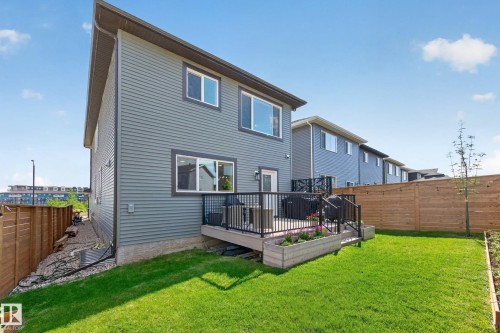 Expansive backyard featuring a manicured lawn, a raised wooden deck with black metal railings, and a privacy fence - 30 Rosewood Way, St. Albert, AB 