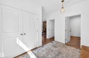 Entryway featuring white paneled doors, hardwood-style flooring, and a glass pendant light fixture - 30 Rosewood Way, St. Albert, AB 
