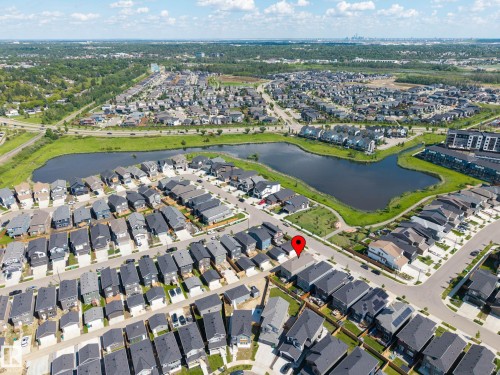 Aerial perspective showcasing a residential community with contemporary homes, a central pond feature, and surrounding green spaces - 30 Rosewood Way, St. Albert, AB 