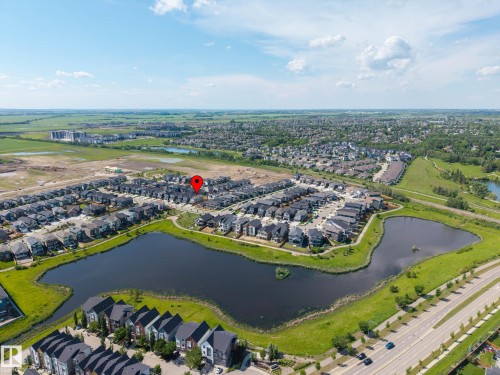 Aerial perspective of a residential development featuring a prominent water body, surrounding green spaces, and a network of roadways - 30 Rosewood Way, St. Albert, AB 