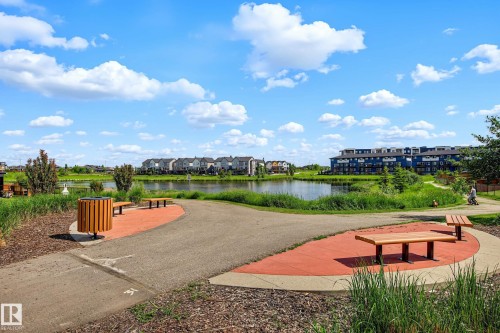 Paved walkway alongside a body of water, featuring integrated benches and landscaped surroundings - 30 Rosewood Way, St. Albert, AB 