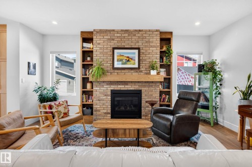 Brick fireplace with wood mantle and integrated shelving, recessed lighting, wood-finish flooring, and white walls - 30 Rosewood Way, St. Albert, AB 