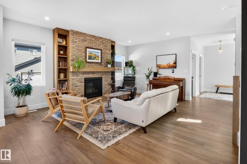 Living room featuring a brick fireplace with a wood mantle, built-in shelving, wood-finish flooring, and recessed lighting - 30 Rosewood Way, St. Albert, AB 
