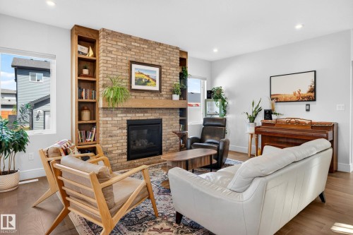 Living area featuring a brick fireplace with a wood mantle and built-in shelving - 30 Rosewood Way, St. Albert, AB 