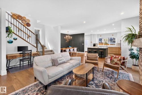 Open-concept living area featuring wood-finish flooring, recessed lighting, and a brick-finished fireplace - 30 Rosewood Way, St. Albert, AB 