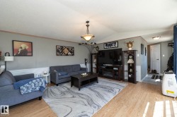 Bright living area featuring wood-finish flooring, a contemporary ceiling light fixture, and wainscoting along the lower wall - 