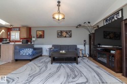 Open-concept living area featuring wood-finish flooring and a central ceiling light fixture - 