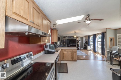 Kitchen featuring wood cabinetry, stainless steel appliances, and a red backsplash - 143 48 3400 Street W, Stony Plain, AB 