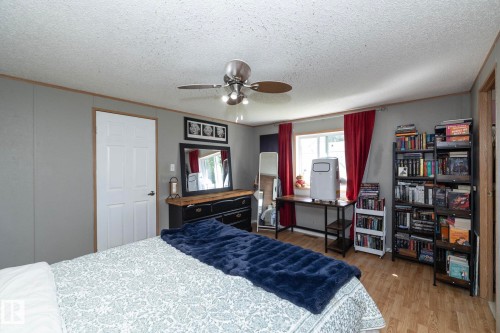 Bedroom featuring wood-finish flooring, a white paneled door, and a ceiling fan with integrated lighting - 143 48 3400 Street W, Stony Plain, AB 