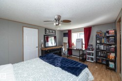 Bedroom featuring wood-finish flooring, a white paneled door, and a ceiling fan with integrated lighting - 