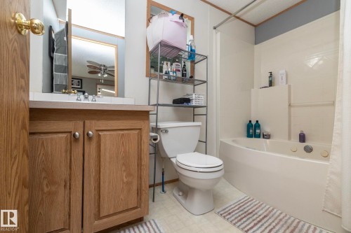 Bathroom featuring a wood-finish vanity with dual cabinet doors, a drop-in sink, and a framed mirror - 143 48 3400 Street W, Stony Plain, AB 