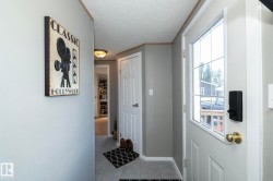 Entryway featuring a white paneled door with a grid-paned window, a smart lock, and a brass door handle - 