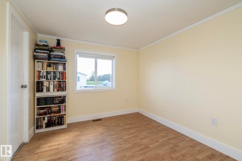Bedroom featuring neutral wall color, wood-finish flooring, white trim, and a window with exterior visibility - 143 48 3400 Street W, Stony Plain, AB 
