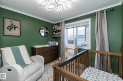 Interior room featuring a wood-finish crib, a window with blinds, and green painted walls - 