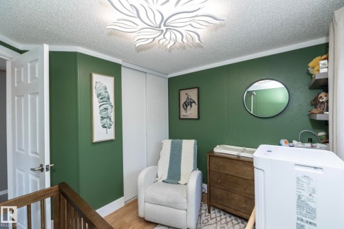 Room featuring wood-finish flooring, a contemporary ceiling light fixture, and a built-in closet with white sliding doors - 143 48 3400 Street W, Stony Plain, AB 