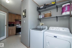 Dedicated laundry area featuring a washer and dryer, open shelving, and neutral wall paneling - 