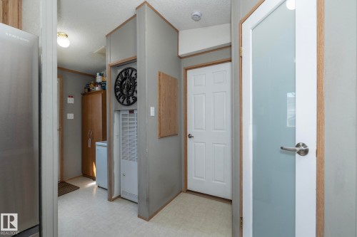 Interior hallway featuring light-toned flooring, white paneled doors, and a frosted glass door - 143 48 3400 Street W, Stony Plain, AB 