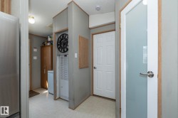 Interior hallway featuring light-toned flooring, white paneled doors, and a frosted glass door - 