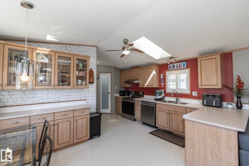 Kitchen featuring natural wood-finish cabinetry, light-toned countertops, and stainless steel appliances - 143 48 3400 Street W, Stony Plain, AB 