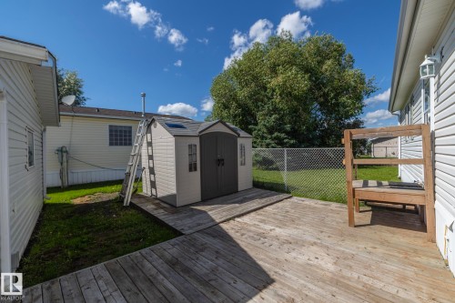 Expansive wooden deck area featuring a detached storage shed with a ramp, and partial chain-link fencing - 143 48 3400 Street W, Stony Plain, AB 