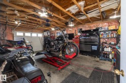 Spacious garage featuring exposed wood beam ceilings and a concrete floor - 